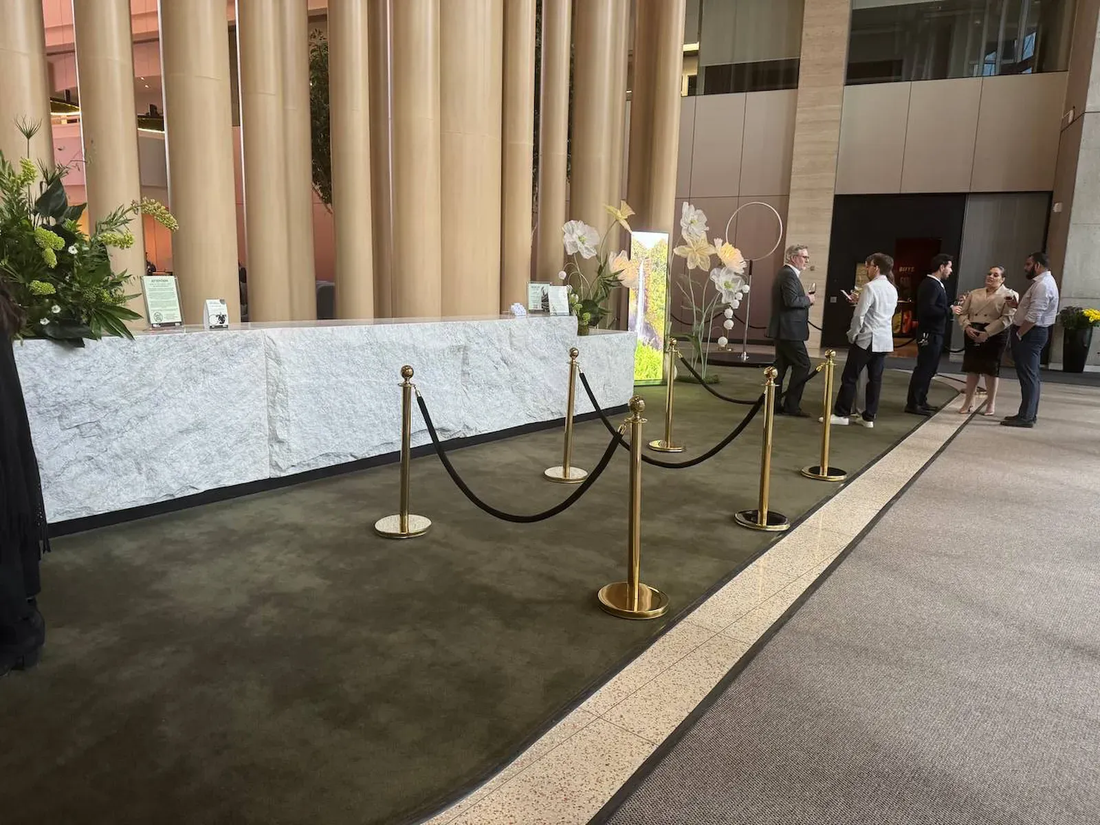 Gold rope stanchions with black velvet ropes at a corporate reception desk
