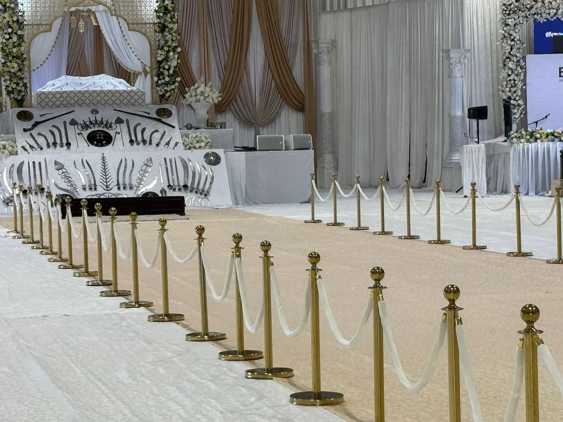 Gold rope stanchions with white velvet ropes lining a ceremony aisle